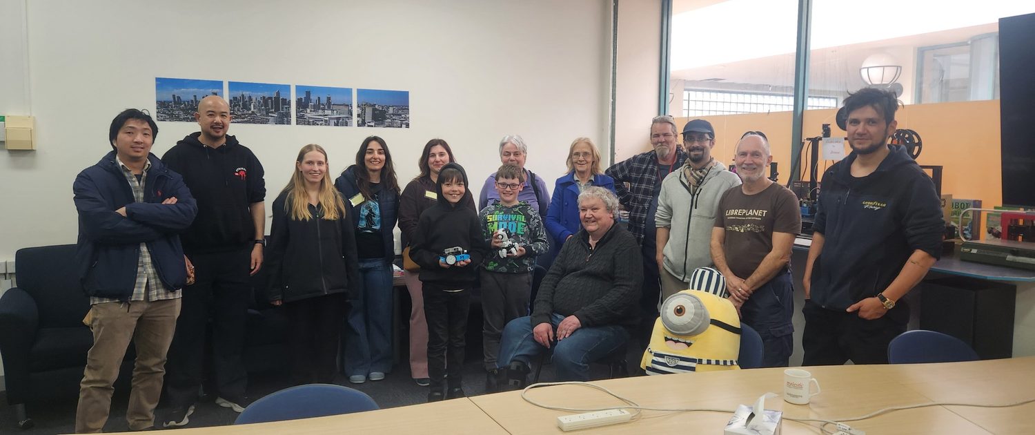 Everyone who came to Software Freedom Day 2025 standing together, including two children holding small robots.